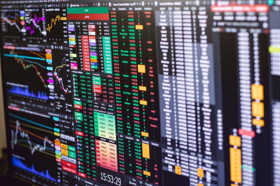 Trader analyzing candlestick charts and risk parameters on multiple trading screens