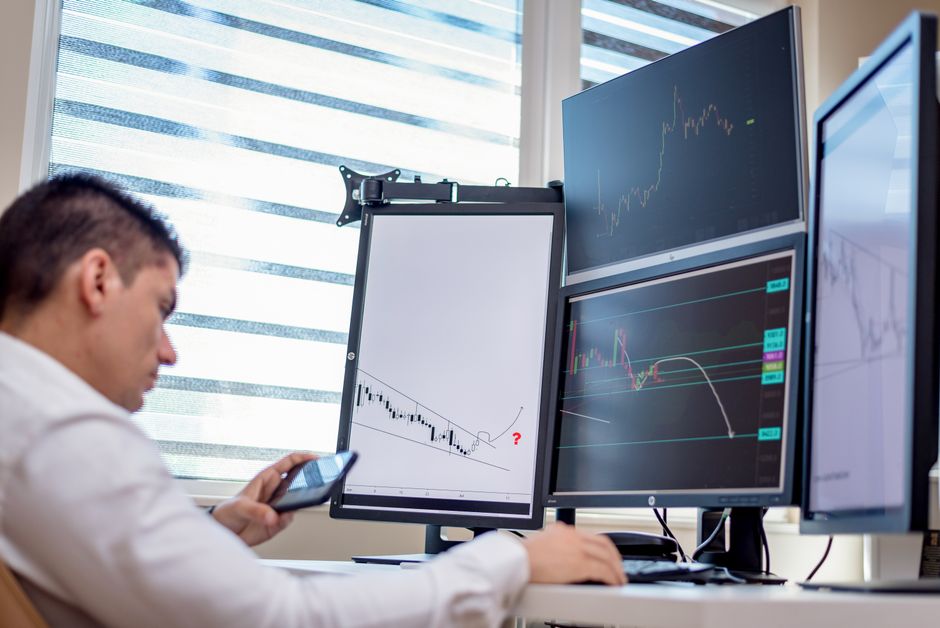 Professional trading setup with multiple monitors displaying market charts and technical indicators